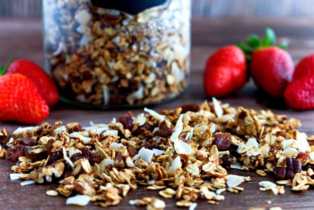 Granola on table with fresh strawberries in background.