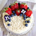 strwberry cake with cashew cream piping and berries on top.