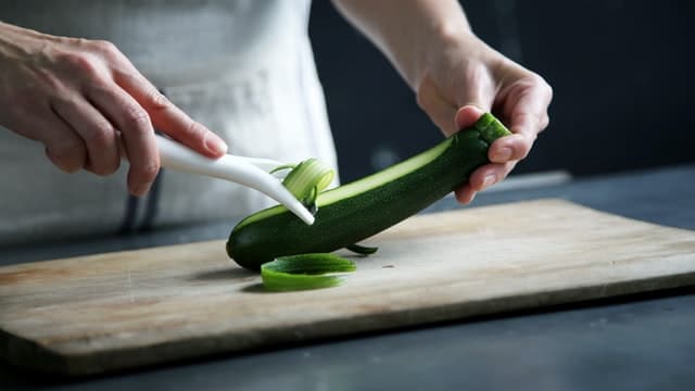 Making thin slices of zucchini with a peeler.