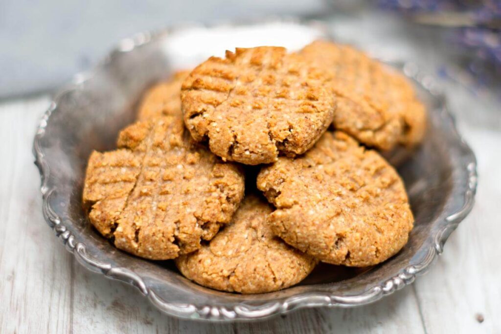 A pile of peanut butter cookies in a silver plate. 