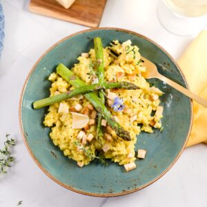 lemon risotto on plate with asparagus, tofu, blue flower decoration.